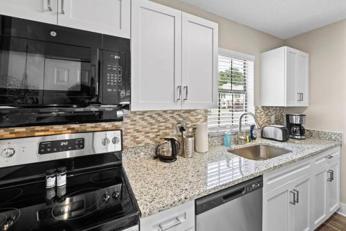 a kitchen with white cabinets and a black appliances at Cozy Townhouse - Gym Pool Golf Fast WiFi 2B2B in Tampa