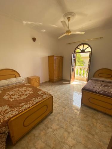 a bedroom with two beds and an open door at Hadi Guest House in Luxor