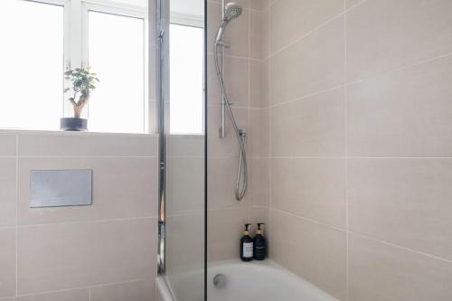 ein weißes Bad mit einer Dusche und einer Badewanne in der Unterkunft Stylish, Cosy flat W/Parking in London, UK in Raynes Park