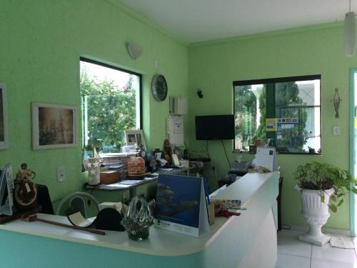 an office with green walls and a desk with a computer at Hotel Pousada Reimar in Balneário Camboriú