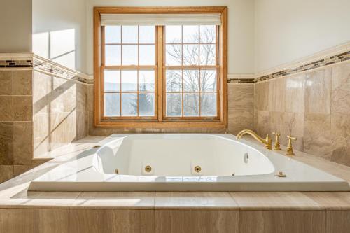 a large white tub in a bathroom with a window at Maplewood Manor 8BR, Hot Tub, Gym, Fire Pit in Jewett