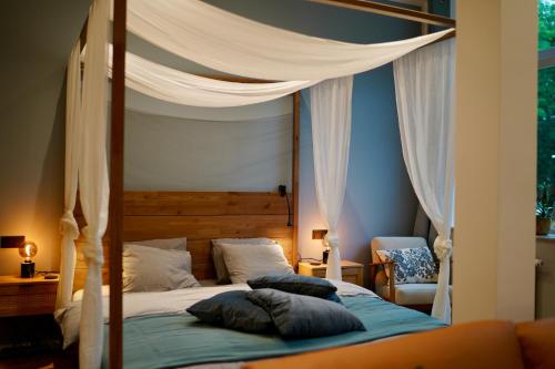 a bedroom with a canopy bed with pillows on it at EDLER WOHNRAUM Luxuriöses Stadtstudio mit Einbaukaffeevollautomat, Balkon, Netflix & Klimaanlage in Zwickau