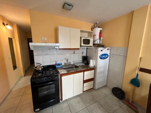 a small kitchen with a stove and a refrigerator at Complejo Berilde I in San Clemente del Tuyú