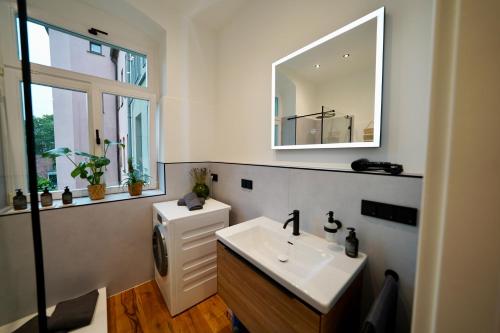 ein Bad mit einem Waschbecken und einem Spiegel in der Unterkunft EDLER WOHNRAUM Luxuriöses Stadtstudio mit Einbaukaffeevollautomat, Balkon, Netflix & Klimaanlage in Zwickau