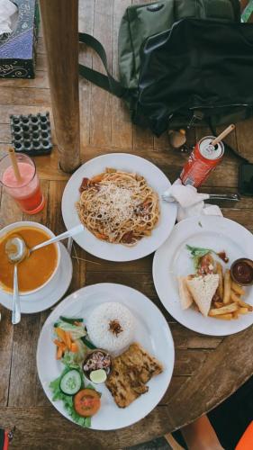 four plates of food on a wooden table at Sakti OceanView Nusa Penida in Nusa Penida