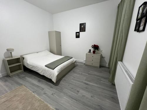 a white bedroom with a bed and a dresser at London Comfort Stay in London