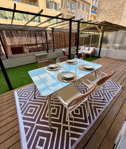 Cocon 2 pièces avec grande terrasse à Vauban في مارسيليا: طاولة وكراسي على سطح خشبي مع طاولة وكراسي