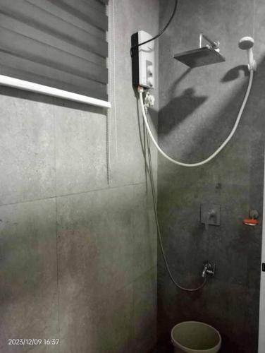 a bathroom with a shower with a hose on the wall at Vacation homes metrogate estate in Silang