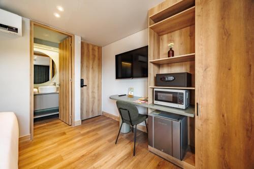 a small room with a desk and a microwave at The Somos Central Hotel Poblado in Medellín