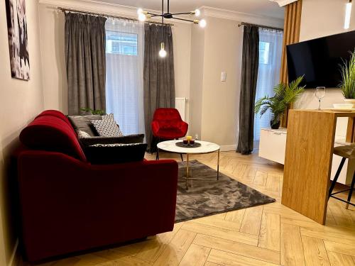 - un salon avec un canapé rouge et une table dans l'établissement Apartamenty Kielce- APARTAMENT SAPHIRE przy zalew kielecki, faktura, parking, centrum, à Kielce