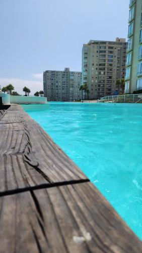 een groot blauw zwembad met gebouwen op de achtergrond bij Departamento en Laguna Vista in Algarrobo
