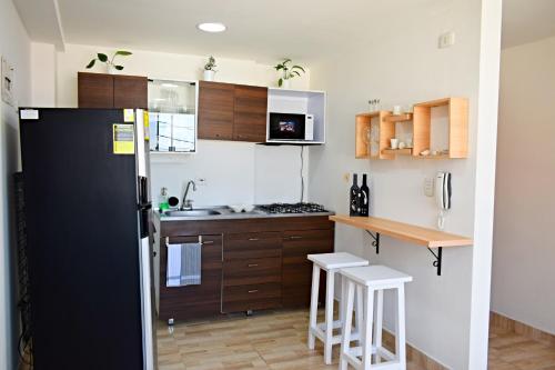 eine Küche mit einem schwarzen Kühlschrank und Holzschränken in der Unterkunft Villa Quintero apartamentos in Santa Rosa de Cabal