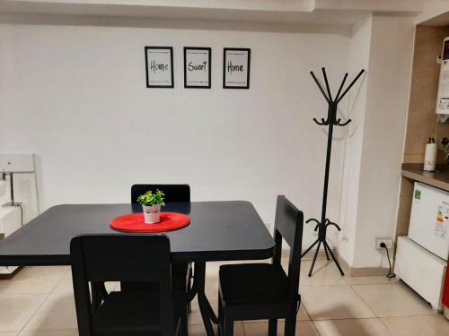 a dining room table with black chairs and a red plate on it at Hermoso departamento céntrico! in San Miguel de Tucumán