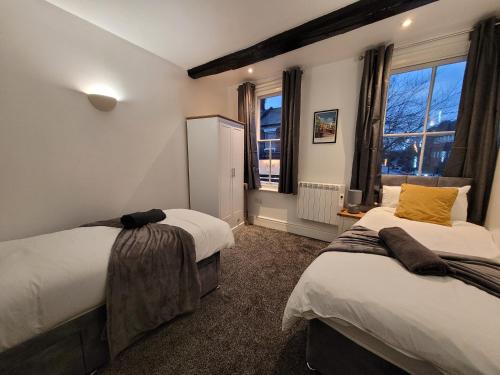 a bedroom with two beds and a window at Wallgate House Apartments- Step back into Roman history with Catchpole Stays in Colchester