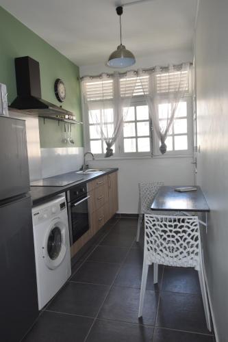 a kitchen with a washing machine and a table with a chair at Perle proche gare maritime et croisières in Pointe-à-Pitre