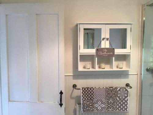 a bathroom with a towel rack and a cabinet at The Coach House at Pitchards in Halstead
