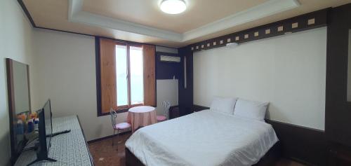 a bedroom with a white bed and a window at SM Resortel in Goheung