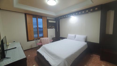 a bedroom with a white bed and a table and window at SM Resortel in Goheung