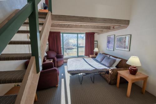 a living room with a bed and a staircase at Sugarloaf Inn in Carrabassett