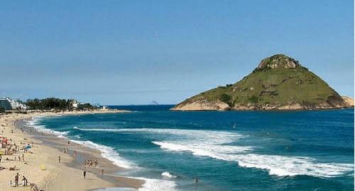a beach with people and an island in the water at Hospedagem Recreio dos Bandeirantes in Rio de Janeiro