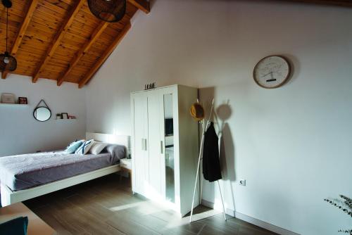 um quarto com uma cama e um relógio na parede em Casita Las Toscas em La Matanza de Acentejo