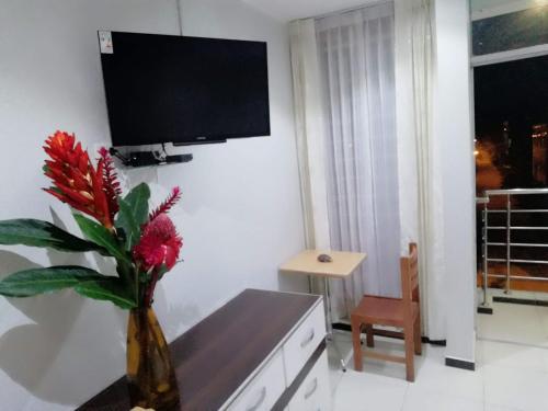 een woonkamer met een vaas met rode bloemen erin bij Hotel Botón de Oro in Puerto Maldonado