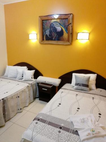 a room with two beds and a painting on the wall at Hotel Botón de Oro in Puerto Maldonado