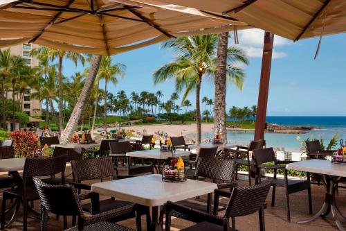 an outdoor restaurant with tables and chairs and the beach at Marriott's Ko Olina Beach Club in Kapolei
