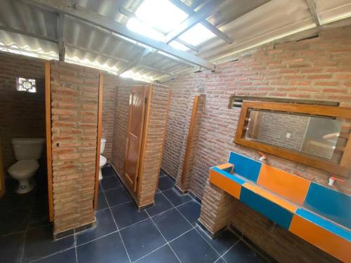 a bathroom with a toilet and a brick wall at Casa campestre San José - Descansa y Diviértete in Santo Tomás