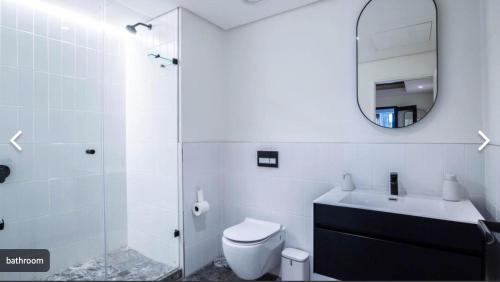 a bathroom with a toilet and a sink and a mirror at Station House Ocean View Apartment in Cape Town