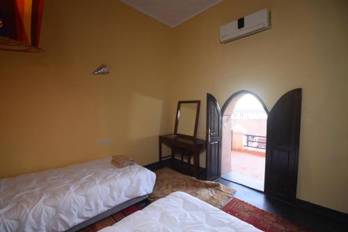 a room with two beds and a mirror and a window at Kasbah Tifoultoute in Ouarzazate