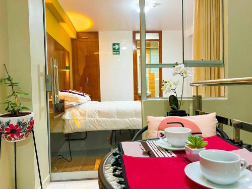 Una habitación con una mesa con dos tazas y una cama en Varvel residence en Cusco