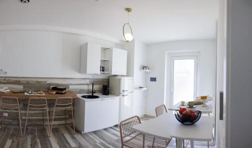 uma cozinha com armários brancos e uma mesa com cadeiras em Essentia Rooms & Relax em Vasto
