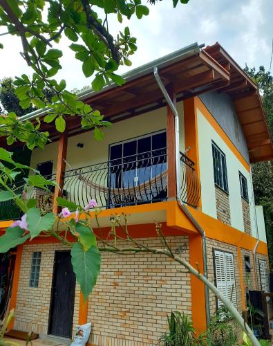 ein orange-weißes Haus mit Balkon in der Unterkunft Stúdio Natureza S/A 2 in Bombinhas