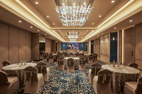 uma sala de banquetes com mesas e cadeiras e um lustre em Radisson Mumbai Goregaon em Mumbai