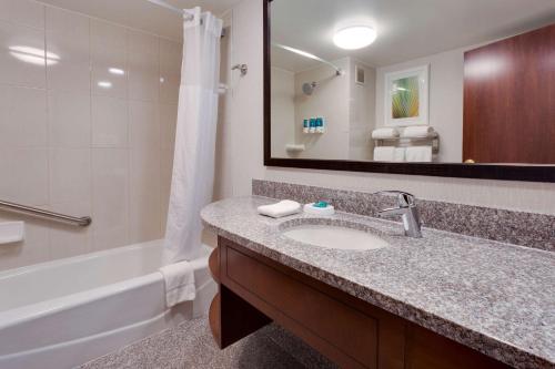 a bathroom with a sink and a tub and a mirror at Drury Inn & Suites Columbia Stadium Boulevard in Columbia