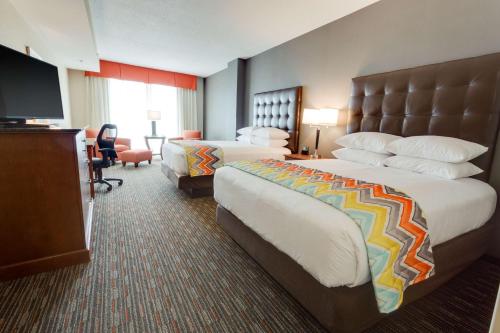 a hotel room with two beds and a television at Drury Inn & Suites Fort Myers Airport FGCU in Fort Myers