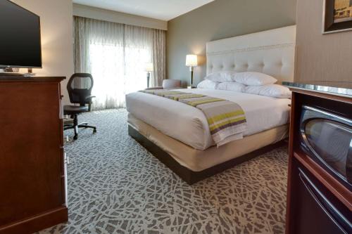 a hotel room with a large bed and a television at Drury Inn & Suites Pittsburgh Airport Settlers Ridge in Pittsburgh