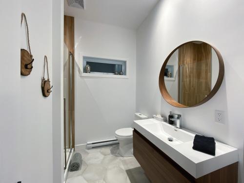 une salle de bain blanche avec un lavabo et un miroir dans l'établissement Le Roselin Exitchalets Spa & Lake, à Notre-Dame-de-la-Merci