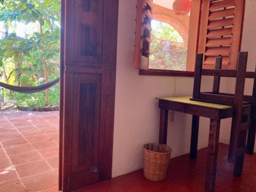 una stanza con una sedia, un tavolo e una finestra di Posada Paloma a San Agustinillo