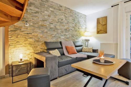 un salon avec un canapé et un mur de briques dans l'établissement La Maison des Embruns - Welkeys, à Capbreton