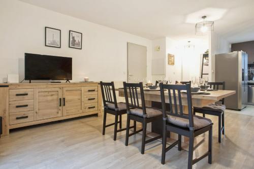 une salle à manger avec une table, des chaises et une télévision à écran plat dans l'établissement La Maison des Embruns - Welkeys, à Capbreton