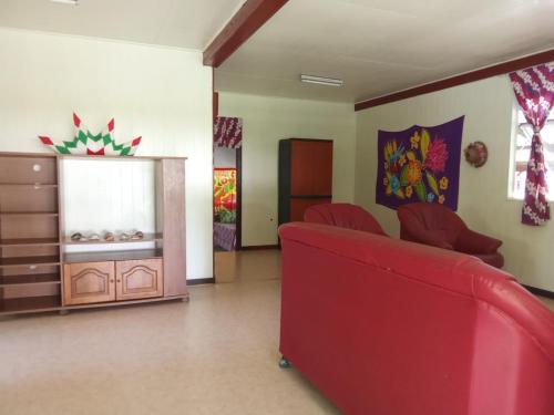 a living room with a red couch and a dresser at Ravehei smile relais 3 Huahine in Haapu