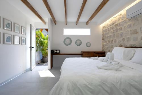 um quarto com uma cama branca e uma parede de pedra em 4 You Hotel Nosara em Playa Guiones