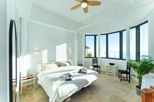 a white bedroom with a large bed and large windows at CasaCarbonito in Carboneras