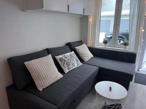 um sofá preto com almofadas numa sala de estar em Lägenhet med egen ingång. em Sundsvall