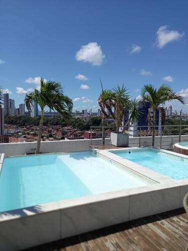 a swimming pool on the roof of a building with palm trees at Manaíra Apart Hotel - 1606 in João Pessoa