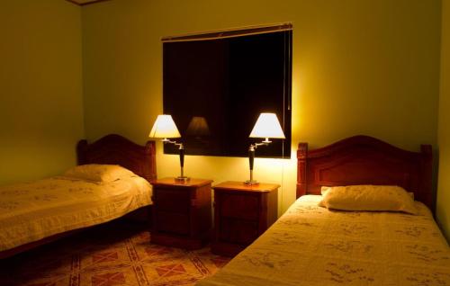 a bedroom with two beds and two lamps on tables at Villas y Cataratas Maquengue Falls in Siquirres