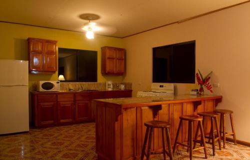 a kitchen with a bar with stools and a refrigerator at Villas y Cataratas Maquengue Falls in Siquirres