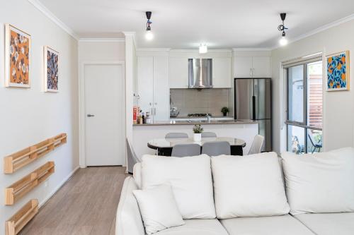 a living room with a white couch and a kitchen at Stylish & Modern Townhouse in Canberra in Harrison